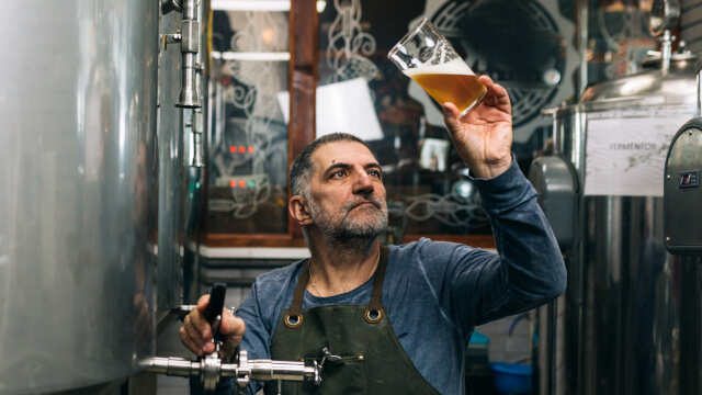 man holding and inspecting glass of beer